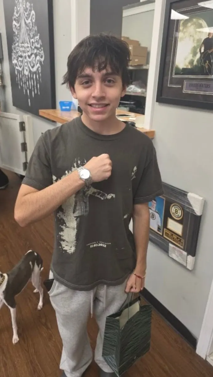 Jacoby showing the watch on his wrist at LBC Pawn, shopping bag in hand and the shop dog beside him