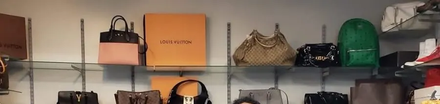 Designer bags bought in Boston — Louis Vuitton and Gucci handbags on the wall at LBC Pawn