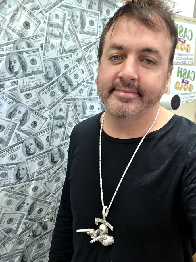Mike, owner of LBC Pawn, in front of the money wall at the shop